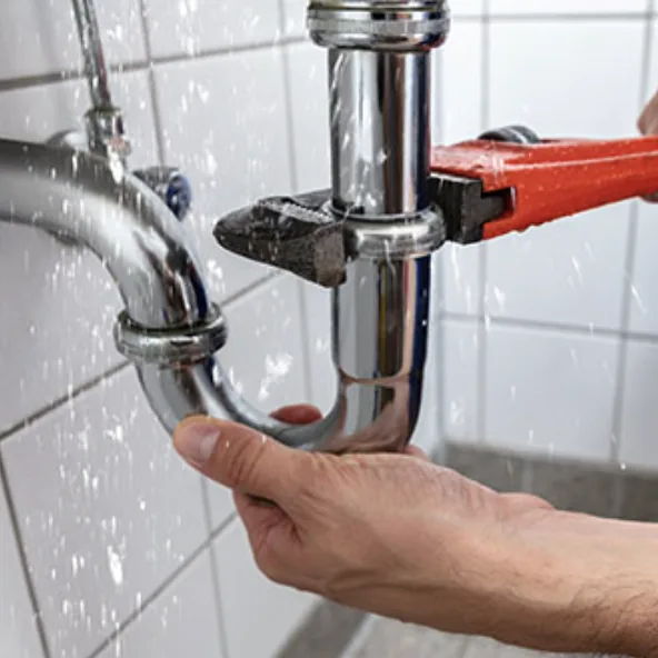 Plumber fixing a leaking pipe with a wrench
