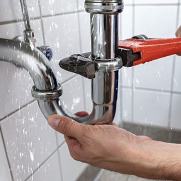 Plumber fixing a leaking pipe with a wrench